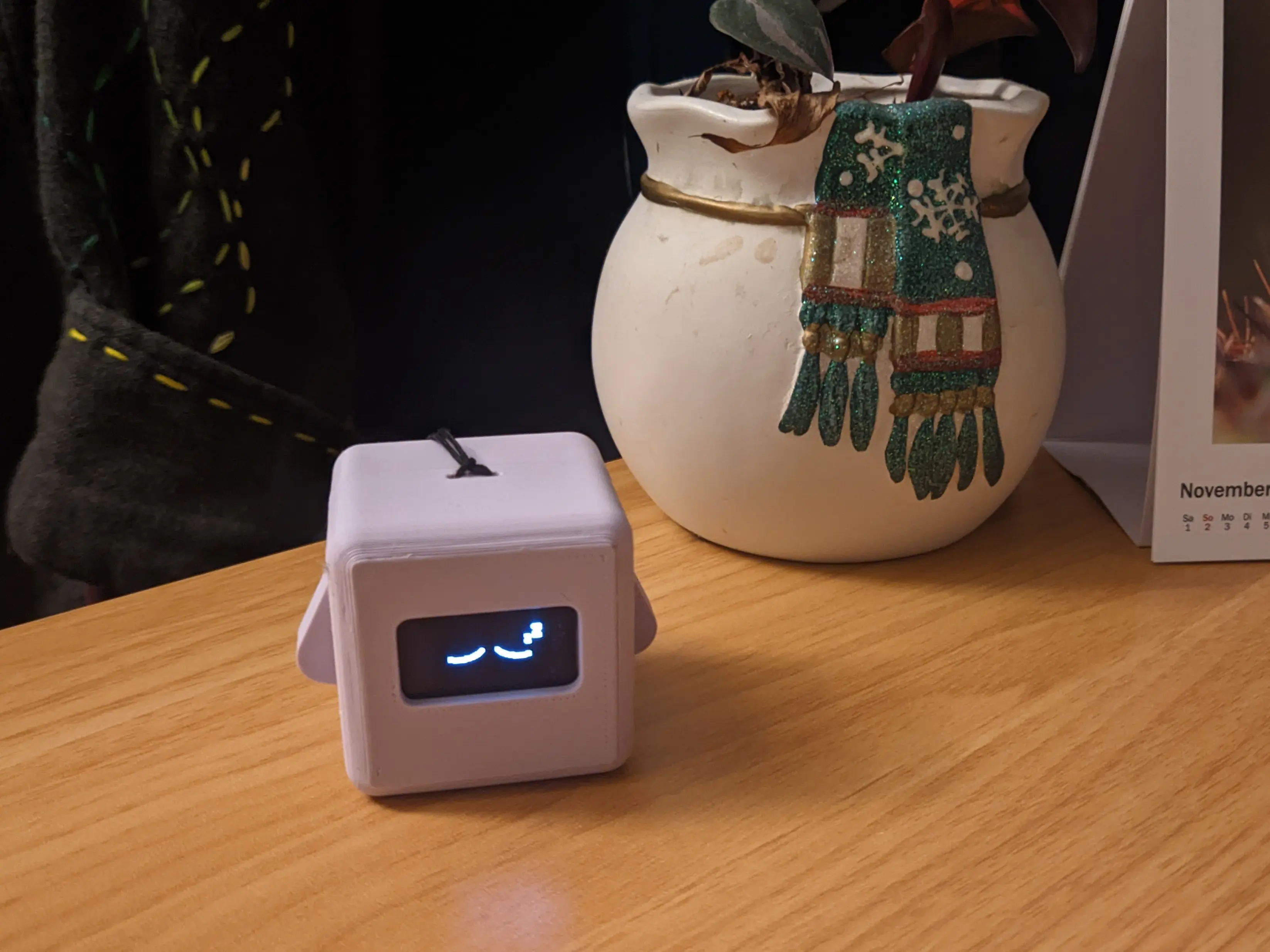 Sleeping Precious Block sitting on a wooden desk, next to a flower pot