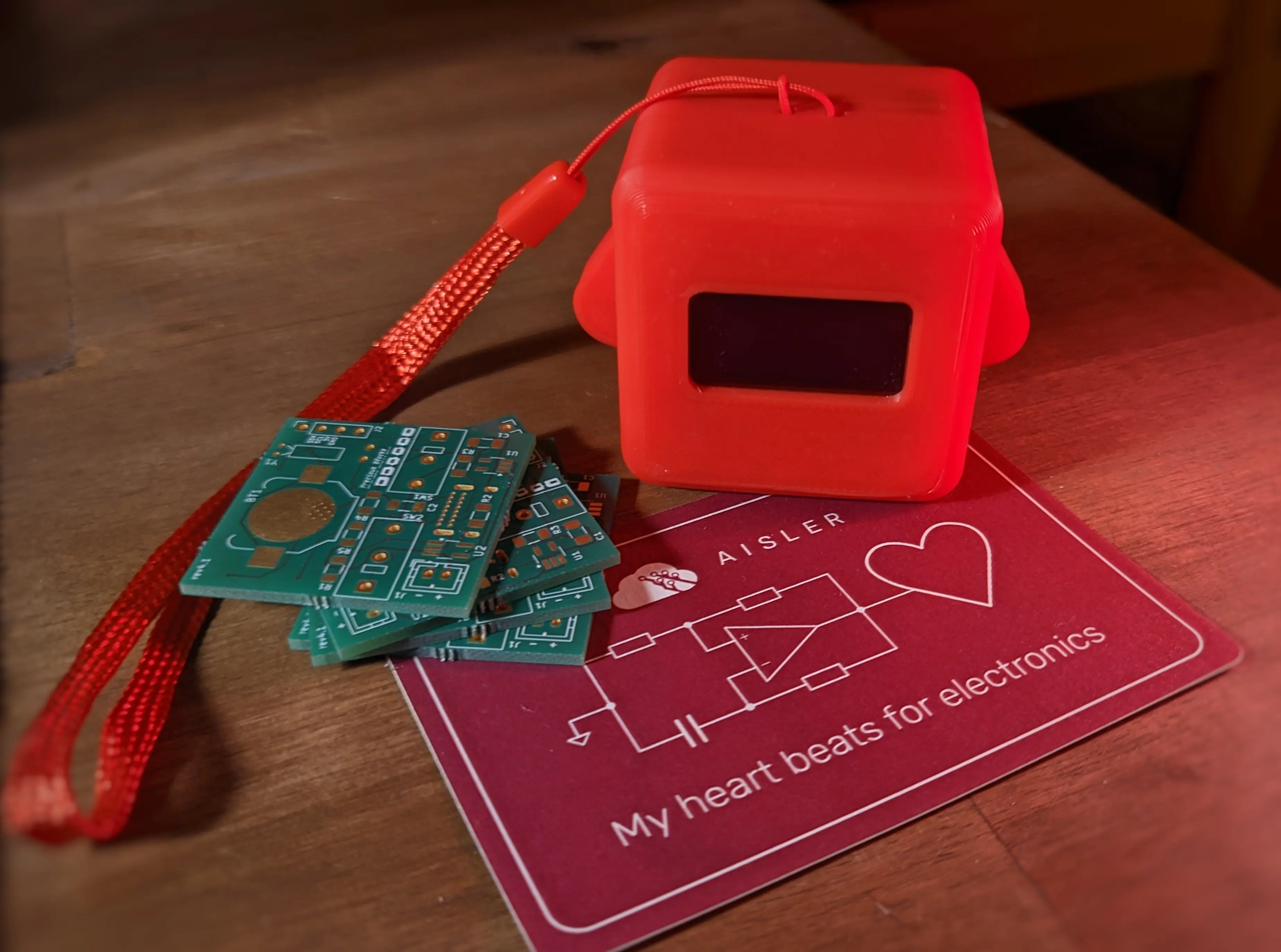 Stack of four green Precious Blocks PCB placed next to a red Precious Block on top of an AISLER sticker. The PCBs are unpopulated, making the outer copper layer visible. You can also make out a Precious Blocks silkscreen with a group of blocks on it
