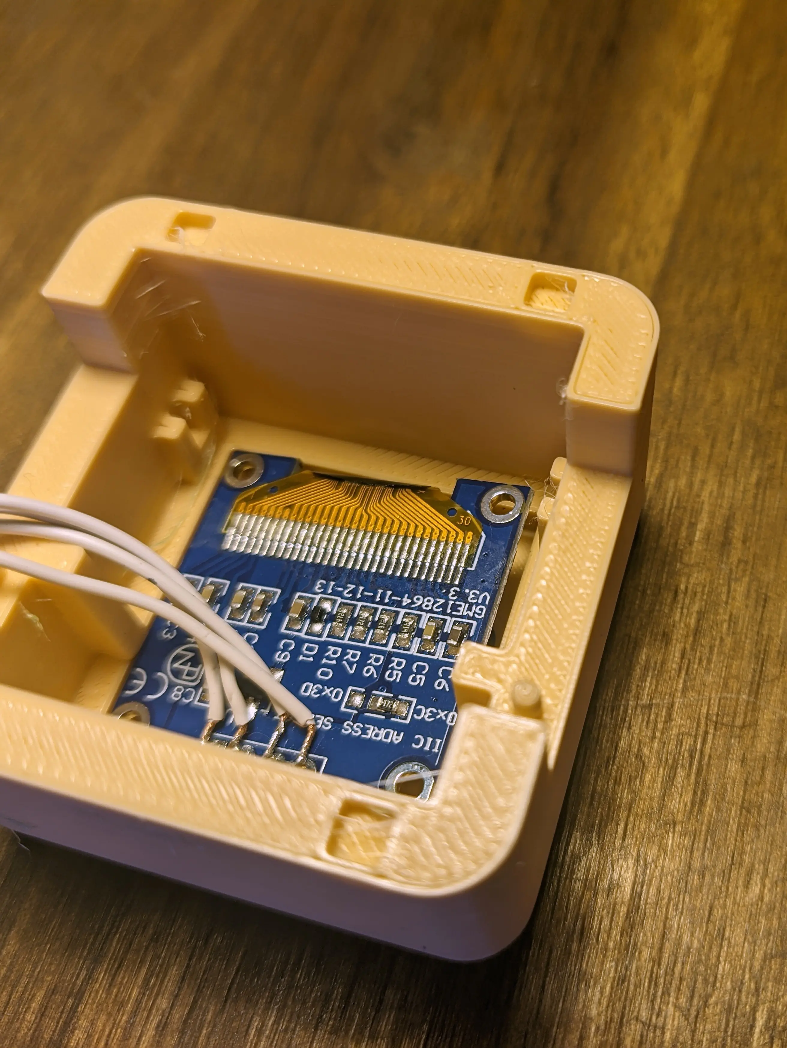Display board slotted into the front case. Its top is facing towards the top of the case and only the right part is fully pressed into the recess. The left part of the display board is lightly placed onto the guide rail, leaving a small space between the front and the display board.
