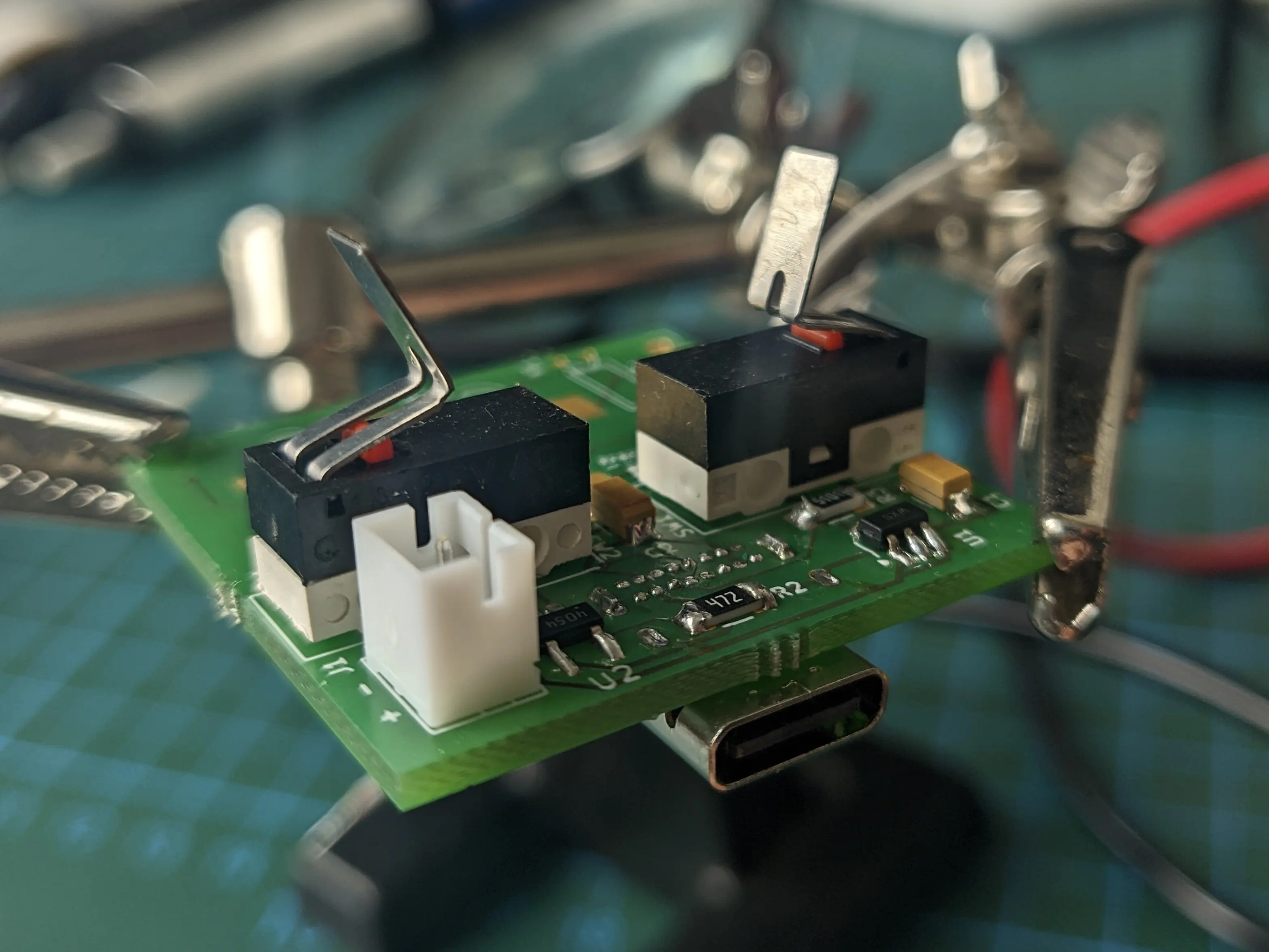 Closeup of the Precious Blocks PCB with two limit switches installed. The switch arms have been bent at the mid-point into roughly 90 degrees angle pieces.